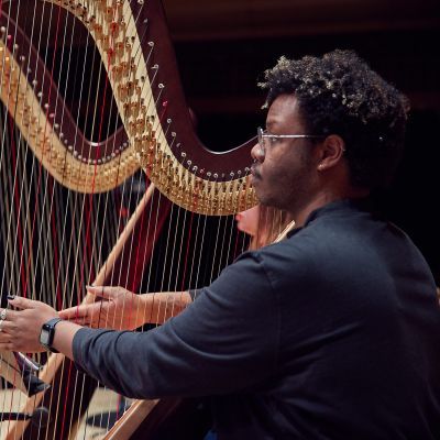 Harpist with hands on the strings in a rehearsal